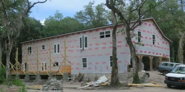 17 Oaks Plantation — exterior wrapped in pink insulation board with windows installed and carport visible